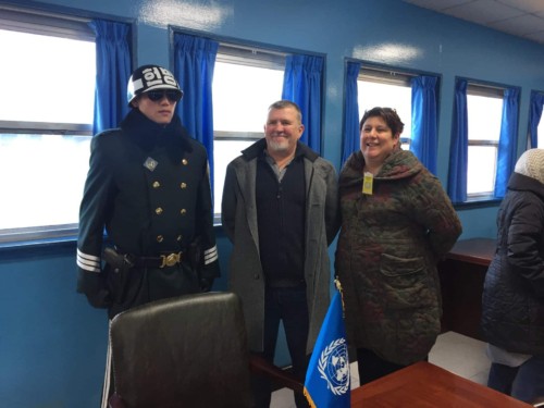 People taking a picture with a border guard inside the UN conference building during a JSA tour