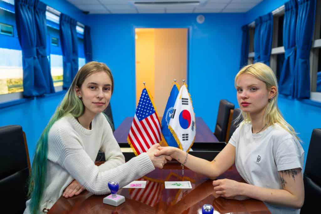 Friend shaking hands for a photo in the replica blue T3 conference room at the JSA Museum