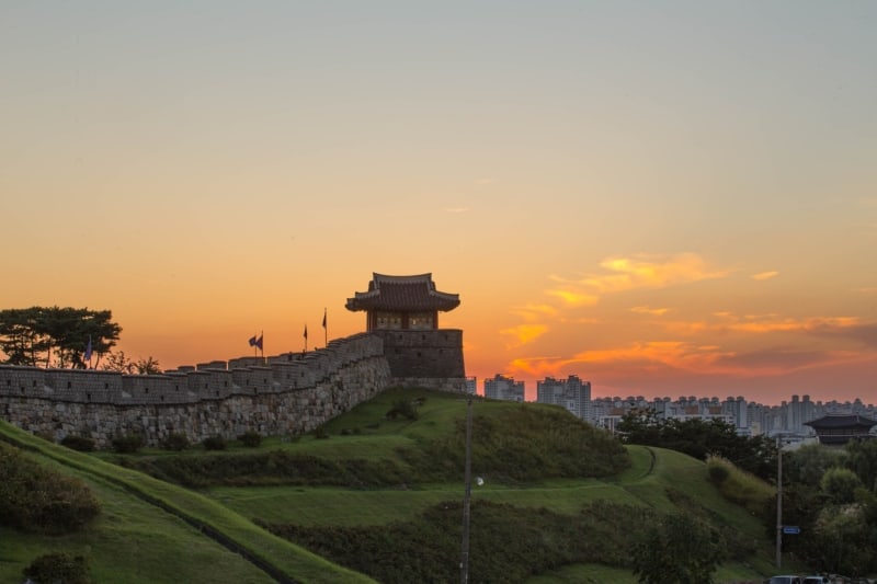 Suwon's Hwaseong Fortress with an orange sky in the background