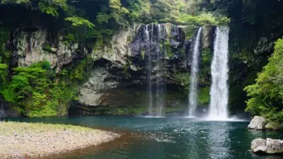 Beautiful Cheonjiyeon Waterfall in Jeju-do, Korea with beautiful green foliage surrounding it