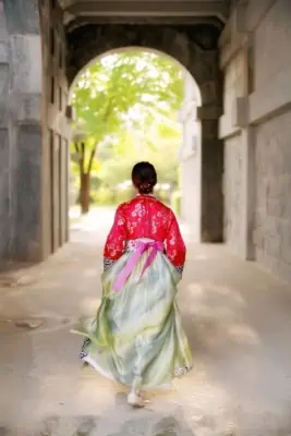 Girl dressed in a Hanbok walking through a palace gate