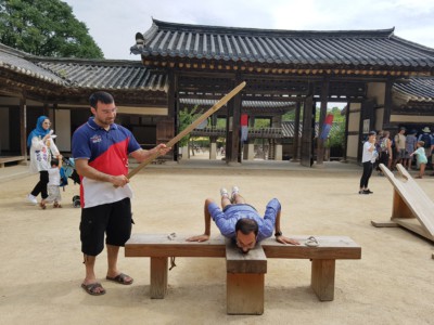 Two visitors trying out one of the Joseon village style punishment methods