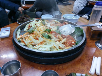 Steam coming off of a delicious Korean Dak-Galbi dish which is being cooked on the table in front of customers