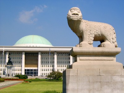 The Korean National Assembly Building in Seoul with a statue infront and unique round blue roof