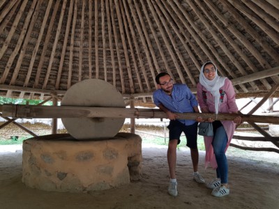 Two visitors trying to grind wheat on a traditional style millstone at Yongin's Folk Village