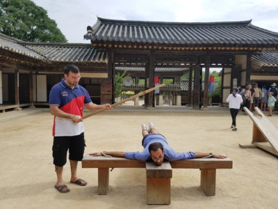 Two men experiencing what traditional punishment was like at the Folk Village in Yongin