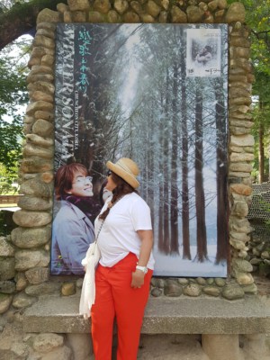 A K-Drama fan at Nami Island posing with a large still from a scene of Winter Sonata