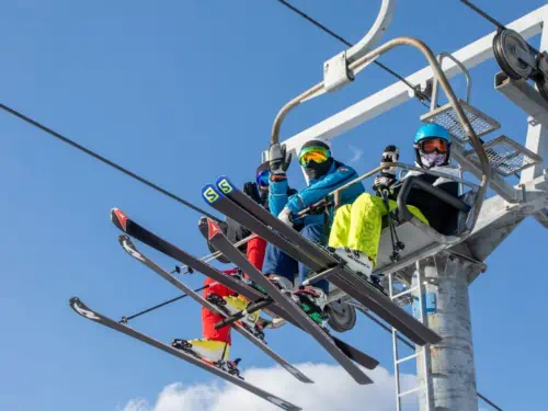 People riding a ski lift to the top of the mountain