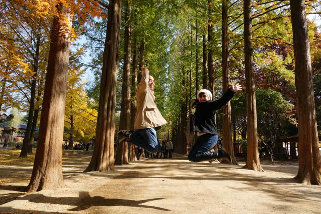 Two people jumping for a photo in front of the famous Ginko Tree Lane on Nami island