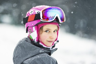 A young girl dressed in a ski suit ready for a lesson