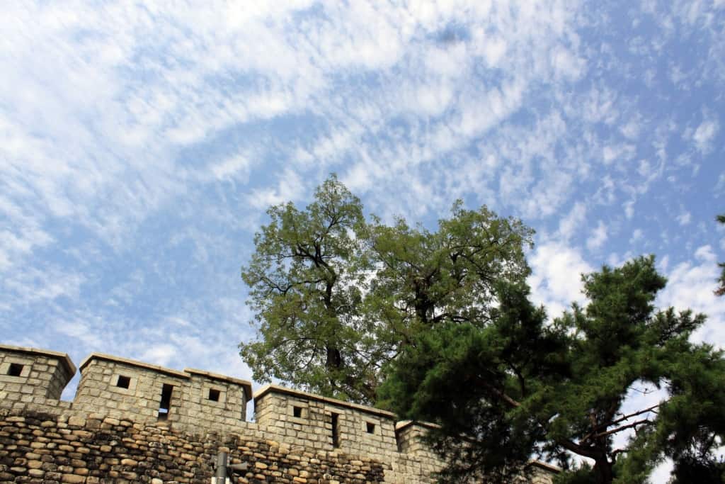 Looking up at a section of the Fortress Wall of Seoul on a clear blue day