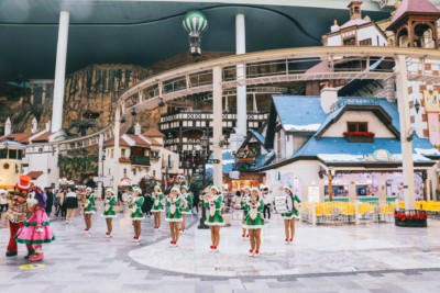 Ladies dressed in green Christmas outfits and hats playing band instruments inside Lotte World in Seoul