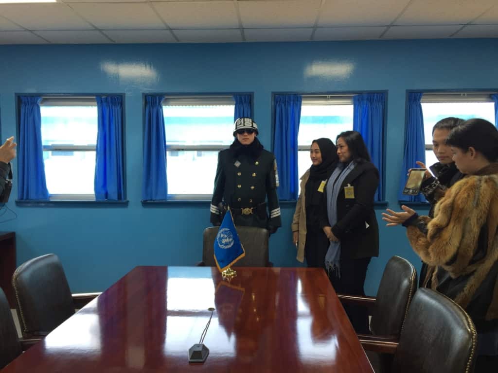 A tour group posing with a border guard inside the UNCMAC conference building