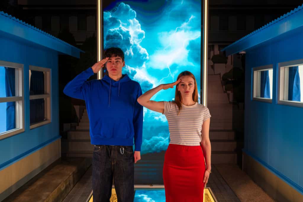 A couple doing a military salute in front of the replica UNCMAC conference rooms at the JSA Museum